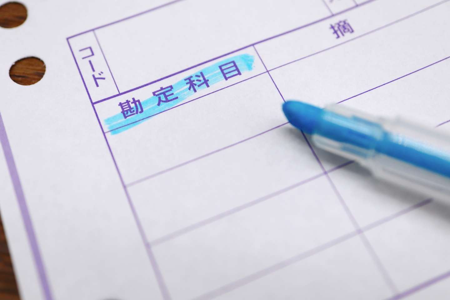 青いマーカーで「勘定科目」が強調された会計帳簿